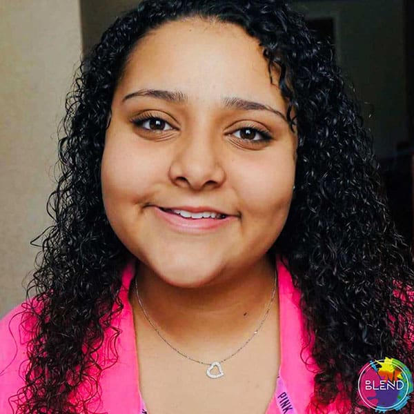 A young lady with long black curly hair wearing pink shares how listening to music has alleviated her depression.