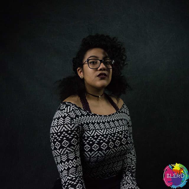 A young black lady with glasses smiles on camera, as she shares the types of therapies that she suggested to improve mental health.