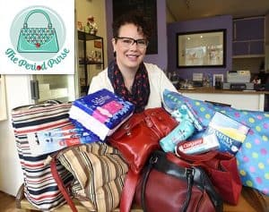 A young lady with short brown curly hair and glasses in her living room preparing to donate menstrual products to the Period Purse.