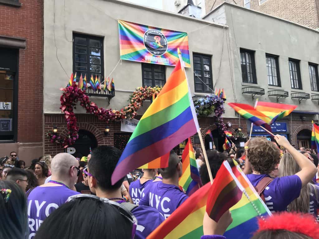 People march down the street holding rainbow colored flags.