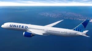 cover Airplane for United Airlines flying over a vast landscape with human settlement far off in the distance