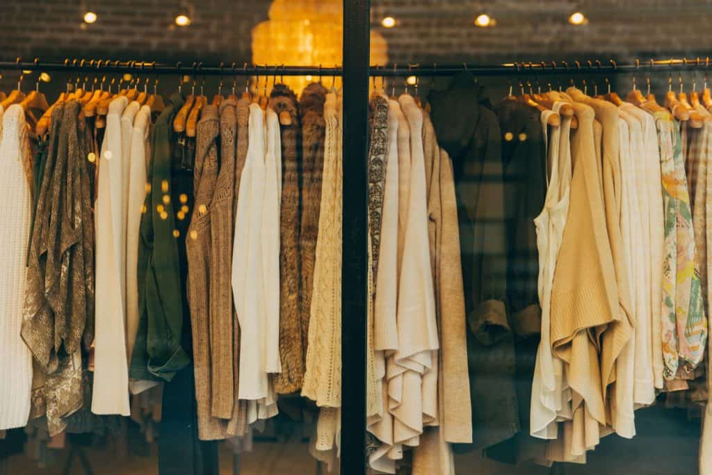 A clothing rack with about 30 sweaters of tan and brown tones