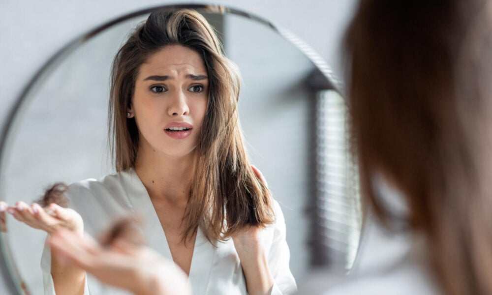 Portrait of stressed young woman with bunch of fallen hair